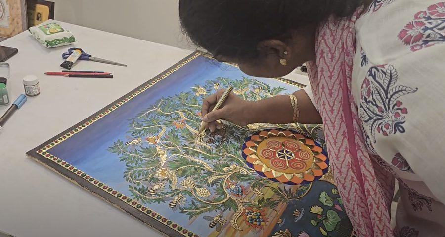 Varalakshmi Bharanidharan hand-applying gold foil detailing to the Ode to Purity Tanjore painting